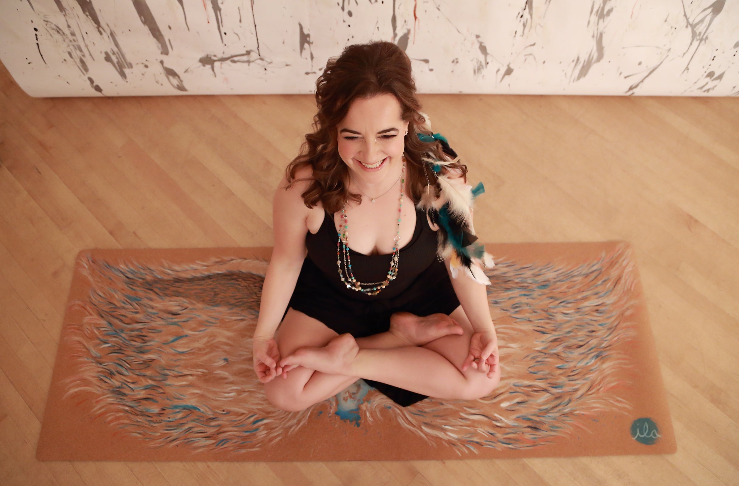 hand painted cork mat angel wings modeled by Satya Yoga and Pilates founder Melissa Boyd in lotus pose happy yogi