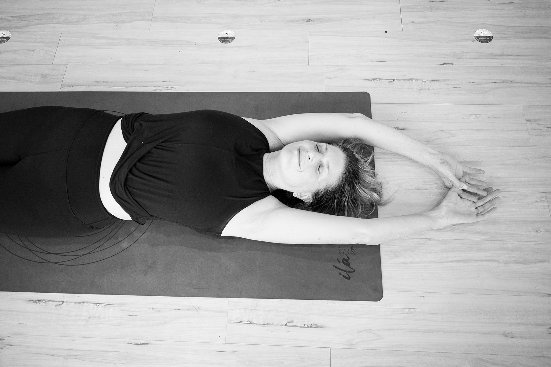 yoga instructor in corpse pose on ilastrate pro mat. antislip yoga mat with sacred geometry design. better than liforme